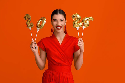 Young happy woman with figure 2024 made of balloons on an orange background. Chinese New Year celebration